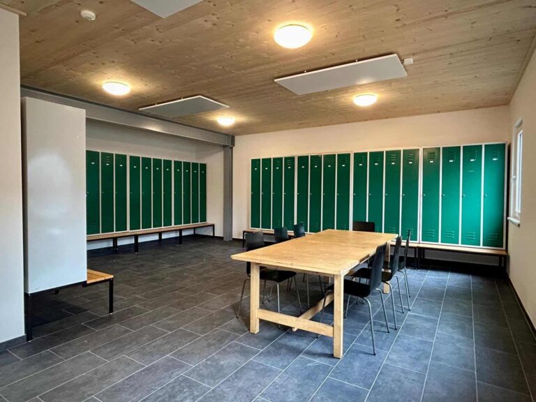 Mitarbeiterumkleide im Kompetenzzentrum von TC Maschinenbau mit grünen Spinden und Sitzbänken.