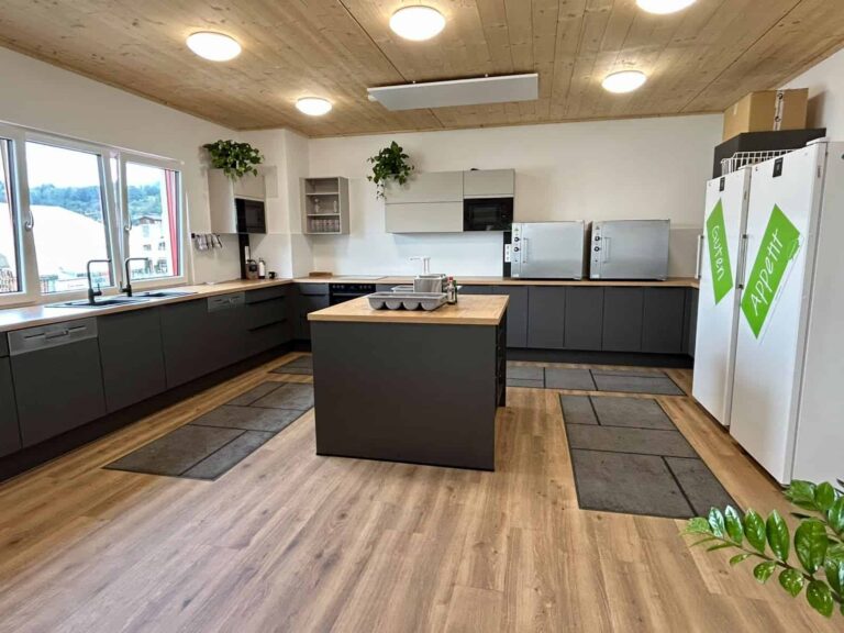 Kantinenküche im Kompetenzzentrum von TC Maschinenbau mit dunklen Küchenzeilen und einer zentralen Kücheninsel.